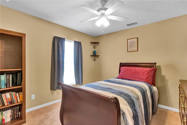 bedroom featuring a textured ceiling, ceiling fan, and light carpet