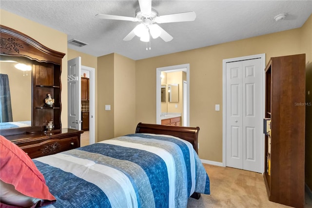 bedroom with light carpet, a textured ceiling, connected bathroom, and ceiling fan