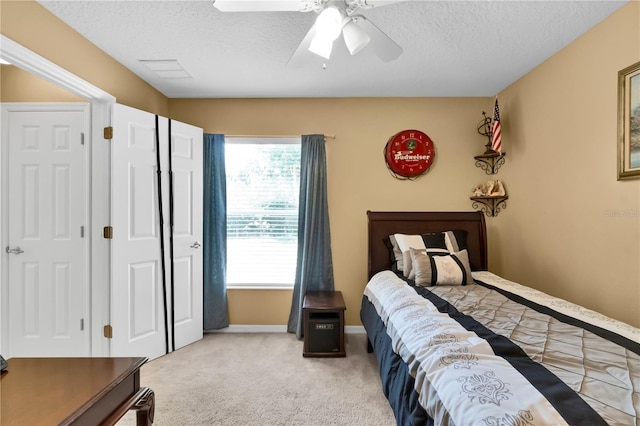 bedroom featuring a textured ceiling, light colored carpet, and ceiling fan