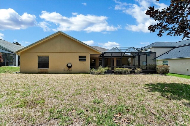 back of house with glass enclosure and a yard