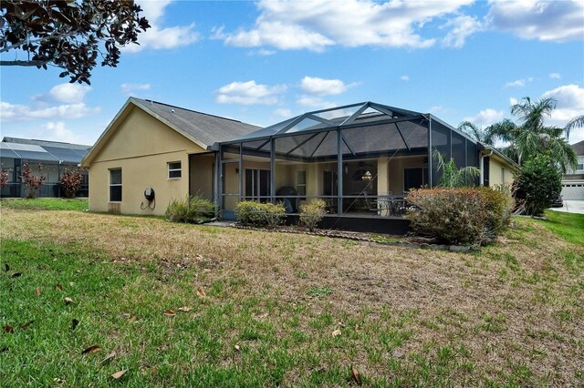 rear view of property with a lanai and a yard