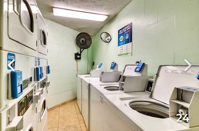 washroom with washing machine and clothes dryer, a textured ceiling, light tile patterned floors, and stacked washer / drying machine