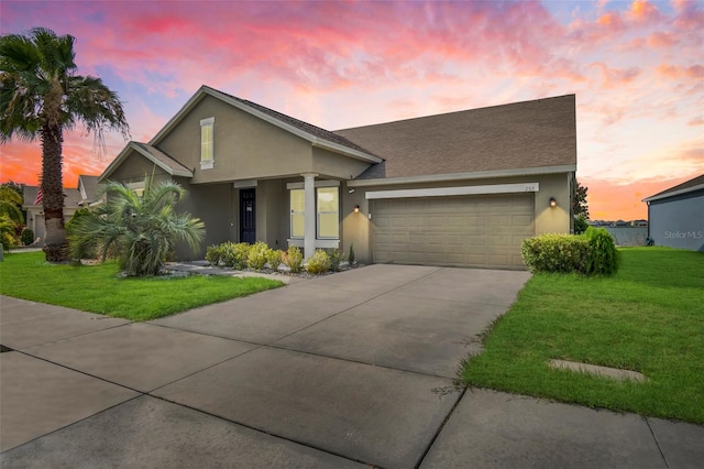 ranch-style home featuring a garage and a lawn