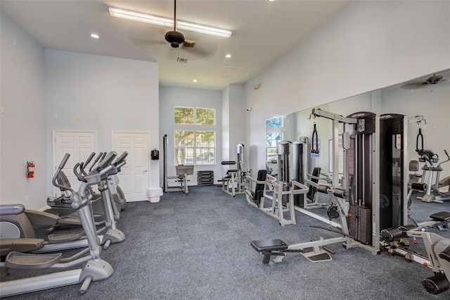 workout area featuring ceiling fan, carpet, and a high ceiling