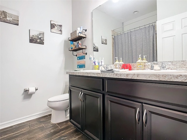 bathroom featuring toilet, wood finished floors, a sink, baseboards, and double vanity