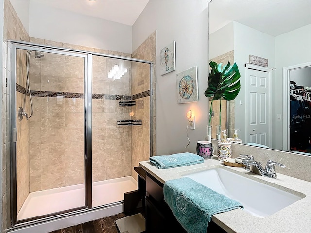 bathroom with a shower stall, a spacious closet, wood finished floors, and vanity