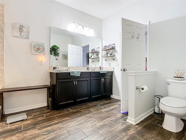 full bathroom with toilet, double vanity, baseboards, and wood finish floors