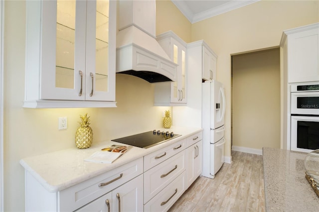 kitchen with white cabinetry, premium range hood, crown molding, white appliances, and light wood-type flooring