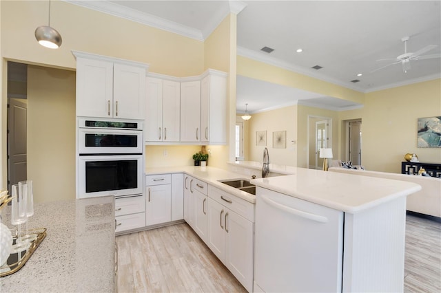 kitchen featuring white cabinetry, multiple ovens, kitchen peninsula, white dishwasher, and decorative light fixtures