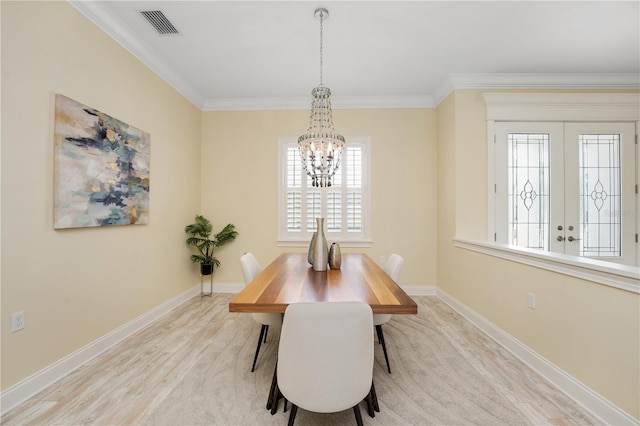 dining space featuring a chandelier, french doors, and crown molding