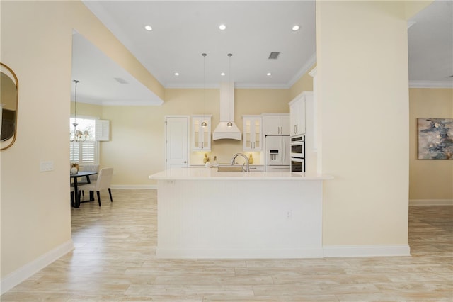 kitchen with white refrigerator with ice dispenser, decorative light fixtures, white cabinets, custom range hood, and ornamental molding