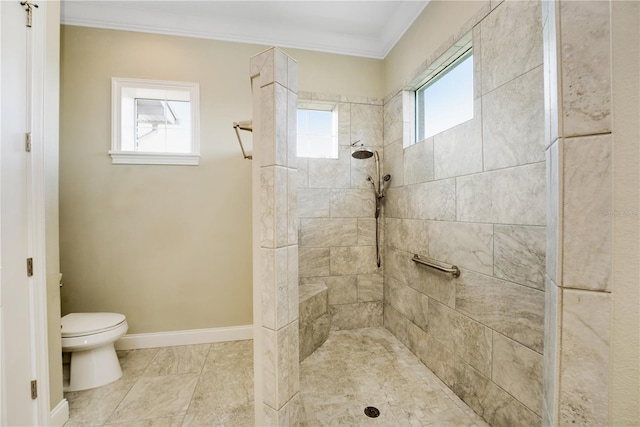 bathroom featuring tile patterned flooring, toilet, ornamental molding, and a tile shower