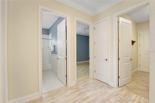 hall with light wood-type flooring and ornamental molding