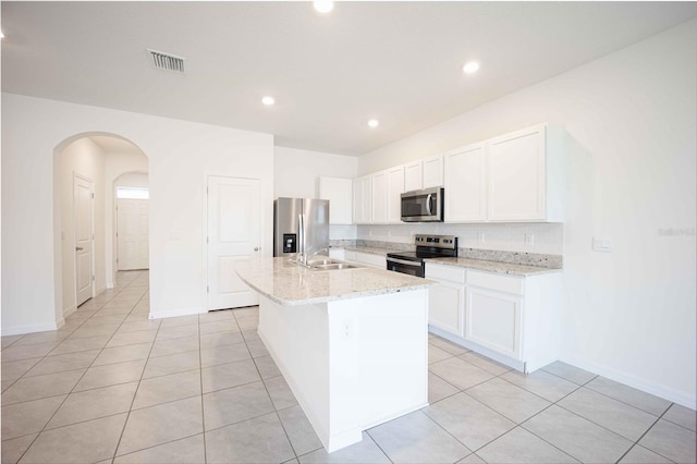 kitchen featuring white cabinets, light stone countertops, an island with sink, and appliances with stainless steel finishes