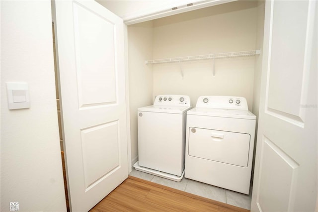 laundry area with light hardwood / wood-style flooring and washing machine and clothes dryer