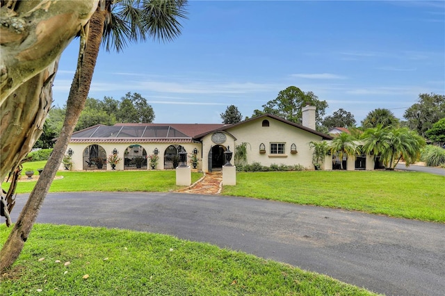 mediterranean / spanish-style home with glass enclosure and a front yard