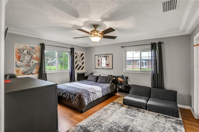 bedroom with a textured ceiling, light wood-type flooring, and ceiling fan