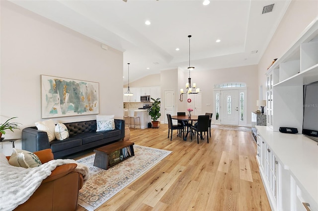 living room with light hardwood / wood-style floors, lofted ceiling, and an inviting chandelier