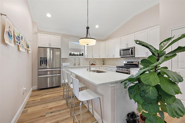 kitchen featuring white cabinetry, sink, stainless steel appliances, vaulted ceiling, and decorative light fixtures