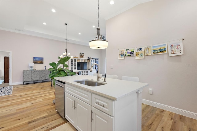 kitchen featuring sink, dishwasher, white cabinets, light hardwood / wood-style floors, and an island with sink