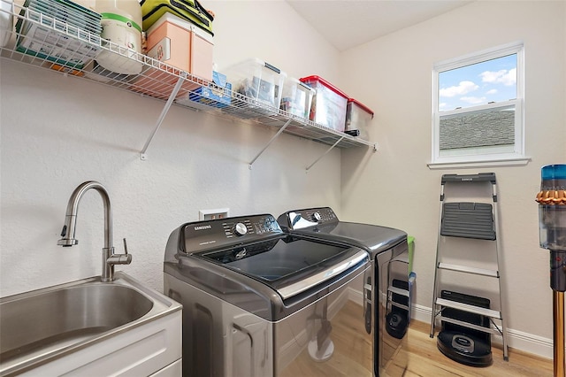 washroom with washer and clothes dryer, sink, and light hardwood / wood-style flooring