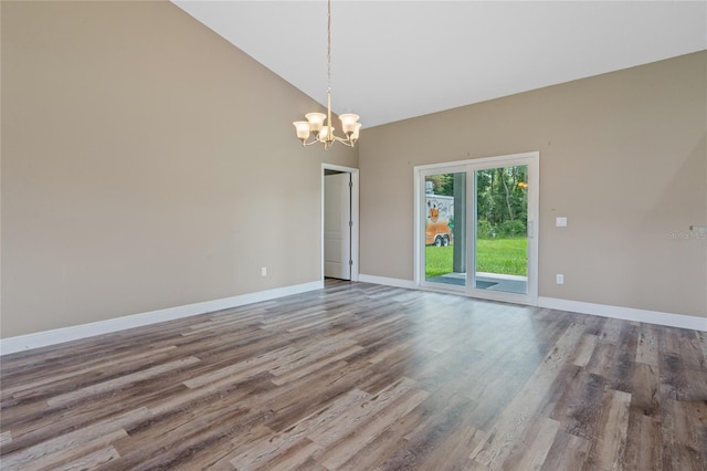 spare room featuring hardwood / wood-style flooring, a notable chandelier, and high vaulted ceiling