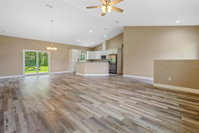 unfurnished living room featuring ceiling fan with notable chandelier, light wood-type flooring, and high vaulted ceiling