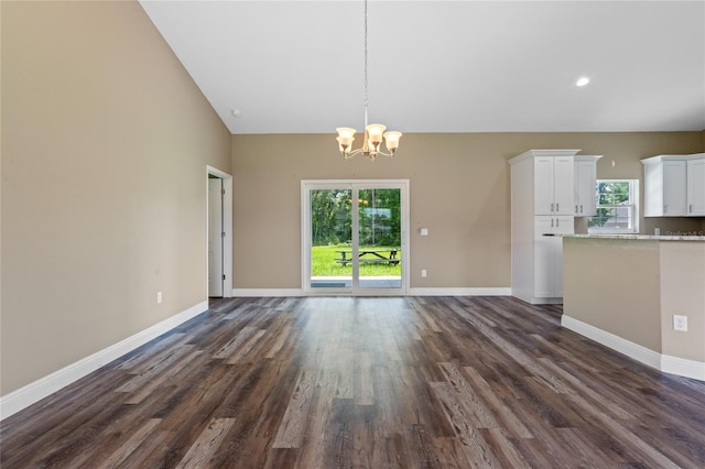 unfurnished living room with dark hardwood / wood-style flooring, an inviting chandelier, and vaulted ceiling