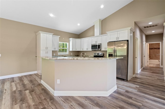 kitchen with white cabinetry, stainless steel appliances, light hardwood / wood-style floors, and a kitchen island with sink