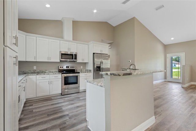 kitchen with high vaulted ceiling, appliances with stainless steel finishes, light wood-type flooring, and white cabinets