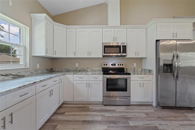 kitchen featuring light wood-type flooring, white cabinets, vaulted ceiling, and stainless steel appliances