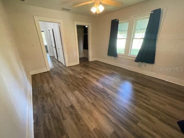 unfurnished bedroom featuring ceiling fan, a spacious closet, a closet, and dark hardwood / wood-style flooring