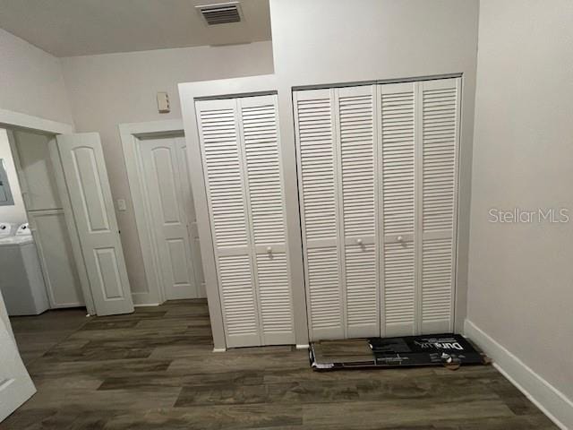 unfurnished bedroom with dark hardwood / wood-style floors and washer / dryer