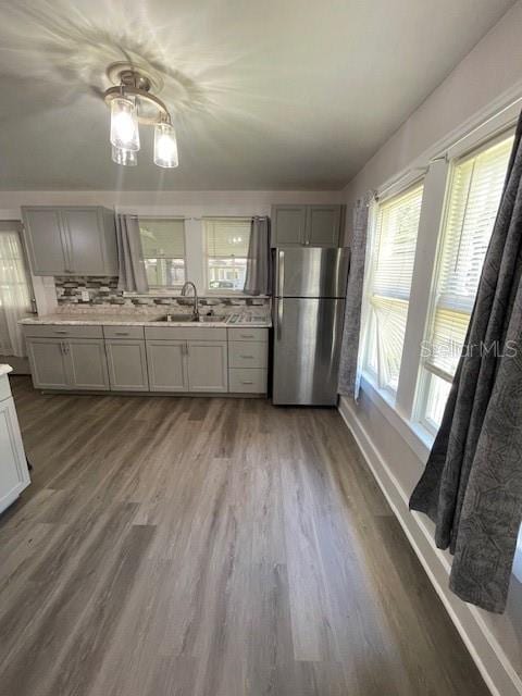 kitchen featuring hardwood / wood-style flooring, gray cabinetry, stainless steel fridge, and sink