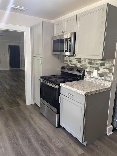 kitchen featuring dark wood-type flooring, stainless steel appliances, and tasteful backsplash