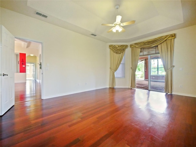 spare room featuring a tray ceiling, ceiling fan, and dark hardwood / wood-style flooring