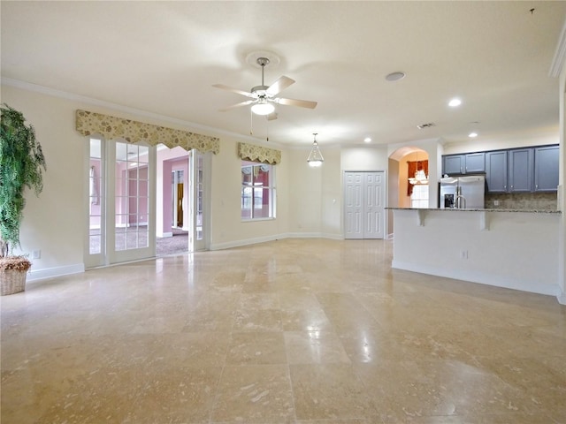 unfurnished living room featuring ceiling fan and ornamental molding