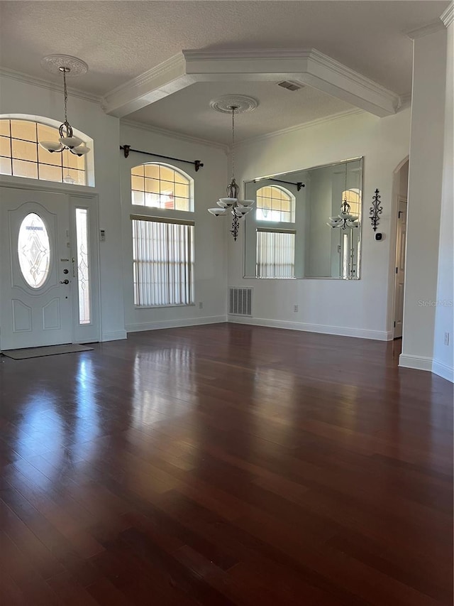 foyer with crown molding, dark wood-type flooring, a textured ceiling, and an inviting chandelier