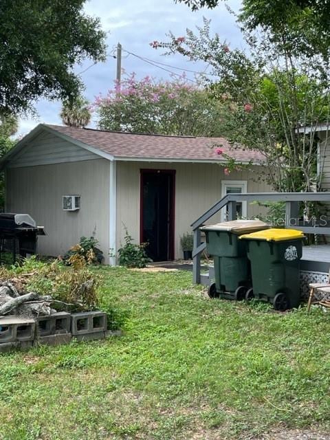 rear view of house featuring a lawn and an AC wall unit