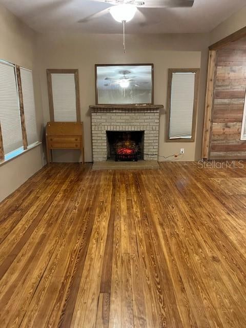 unfurnished living room featuring a fireplace, wood-type flooring, and ceiling fan