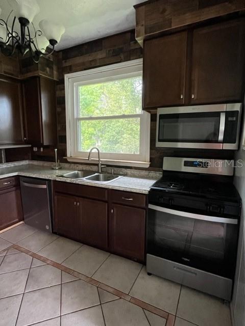 kitchen with sink, light tile patterned flooring, stainless steel appliances, and dark brown cabinets