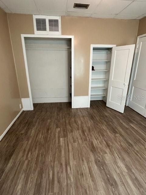 unfurnished bedroom with a paneled ceiling and dark wood-type flooring