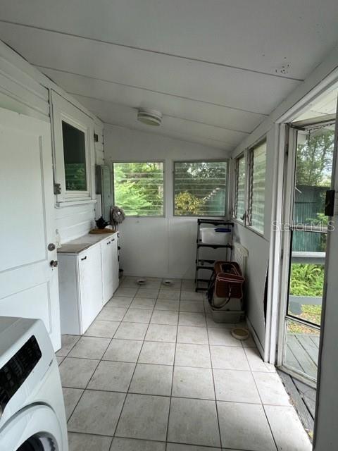 unfurnished sunroom featuring washer / clothes dryer and lofted ceiling