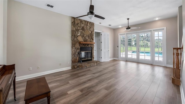 unfurnished living room featuring a stone fireplace, ceiling fan, and hardwood / wood-style flooring