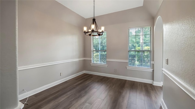 spare room featuring a chandelier, dark hardwood / wood-style floors, a wealth of natural light, and lofted ceiling