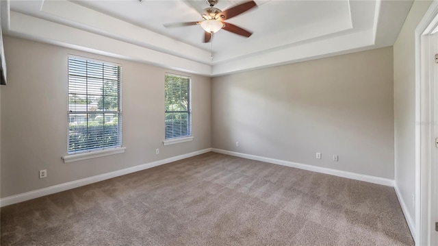 carpeted spare room featuring ceiling fan and a raised ceiling