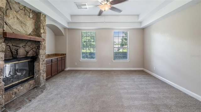 unfurnished living room with a raised ceiling, light carpet, a fireplace, and ceiling fan