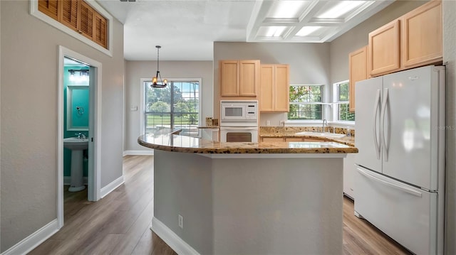 kitchen featuring light stone counters, coffered ceiling, white appliances, sink, and decorative light fixtures