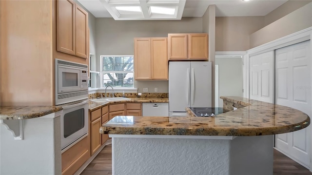 kitchen with light brown cabinets, white appliances, and sink