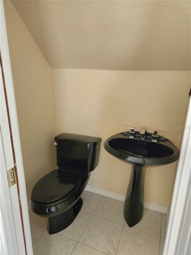 bathroom featuring toilet, tile patterned floors, and vaulted ceiling